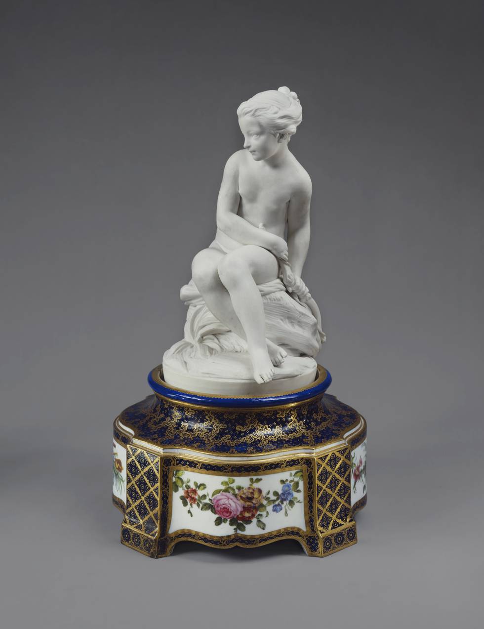 Porcelain sculpture of young women on floral painted pedestal