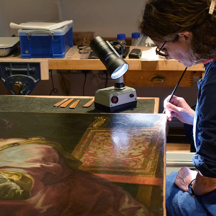 An image of a woman conserving a painting