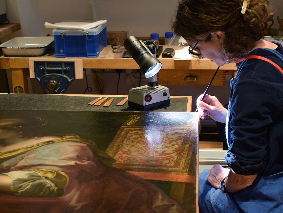An image of a woman conserving a painting