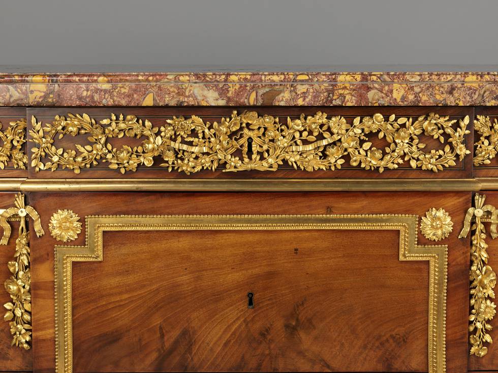 A detail of the gilt-bronze frieze mounts of a mahogany-veneered chest of drawers