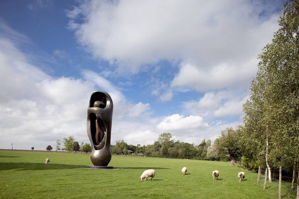 Large Henry Moore sculpture in grass field with sheep