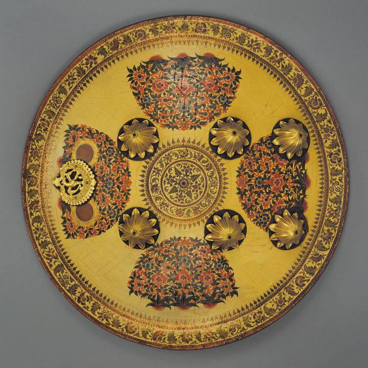 Round yellow shield with floral illustrations and gilt metal bosses