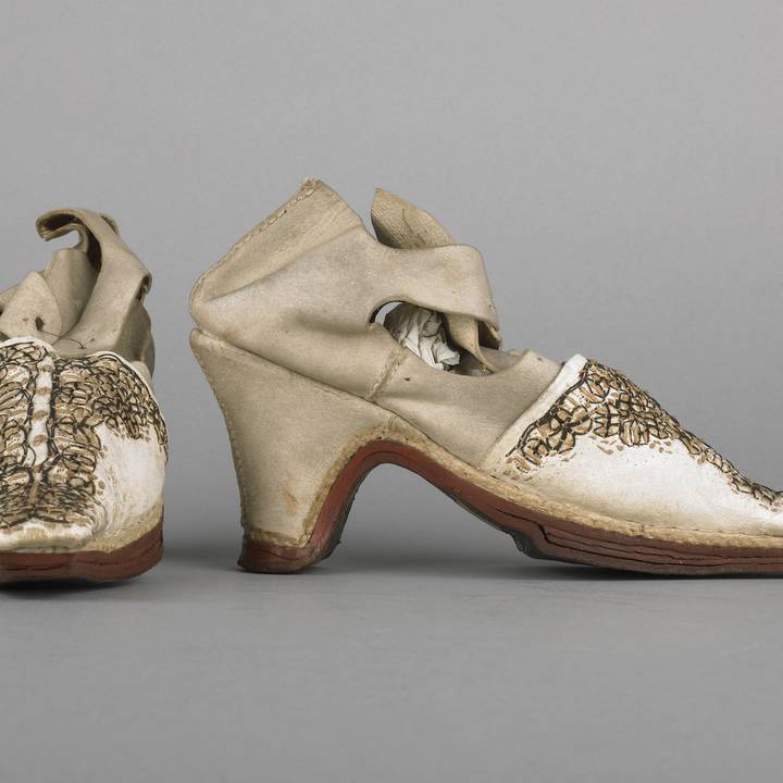 View of the side and front of a pair of white leather ladies shoes with embroidered toes