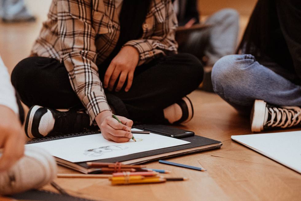 Student sitting on the floor while sketching